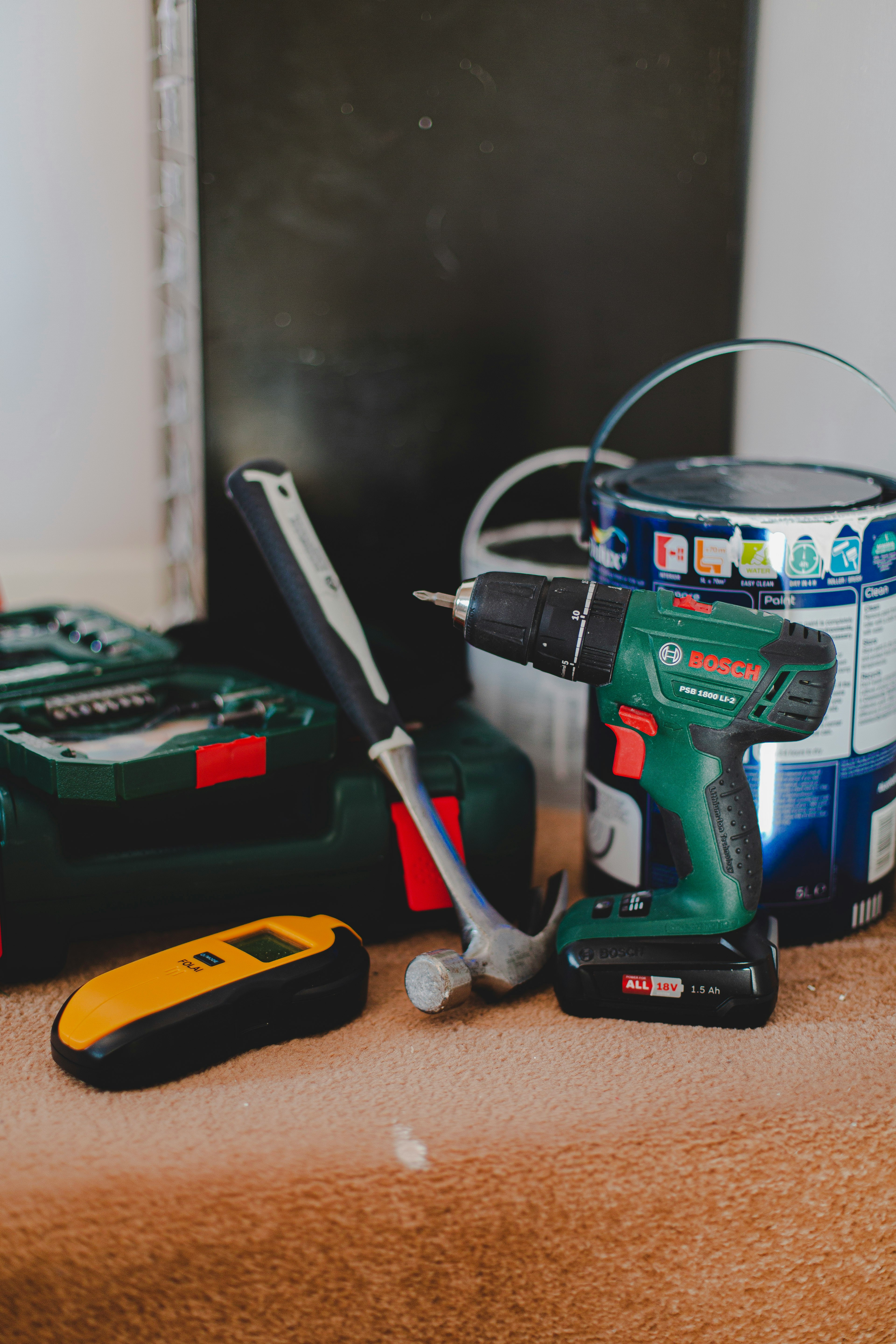 A hammer, drill, paint can and other tools on a carpeted stair