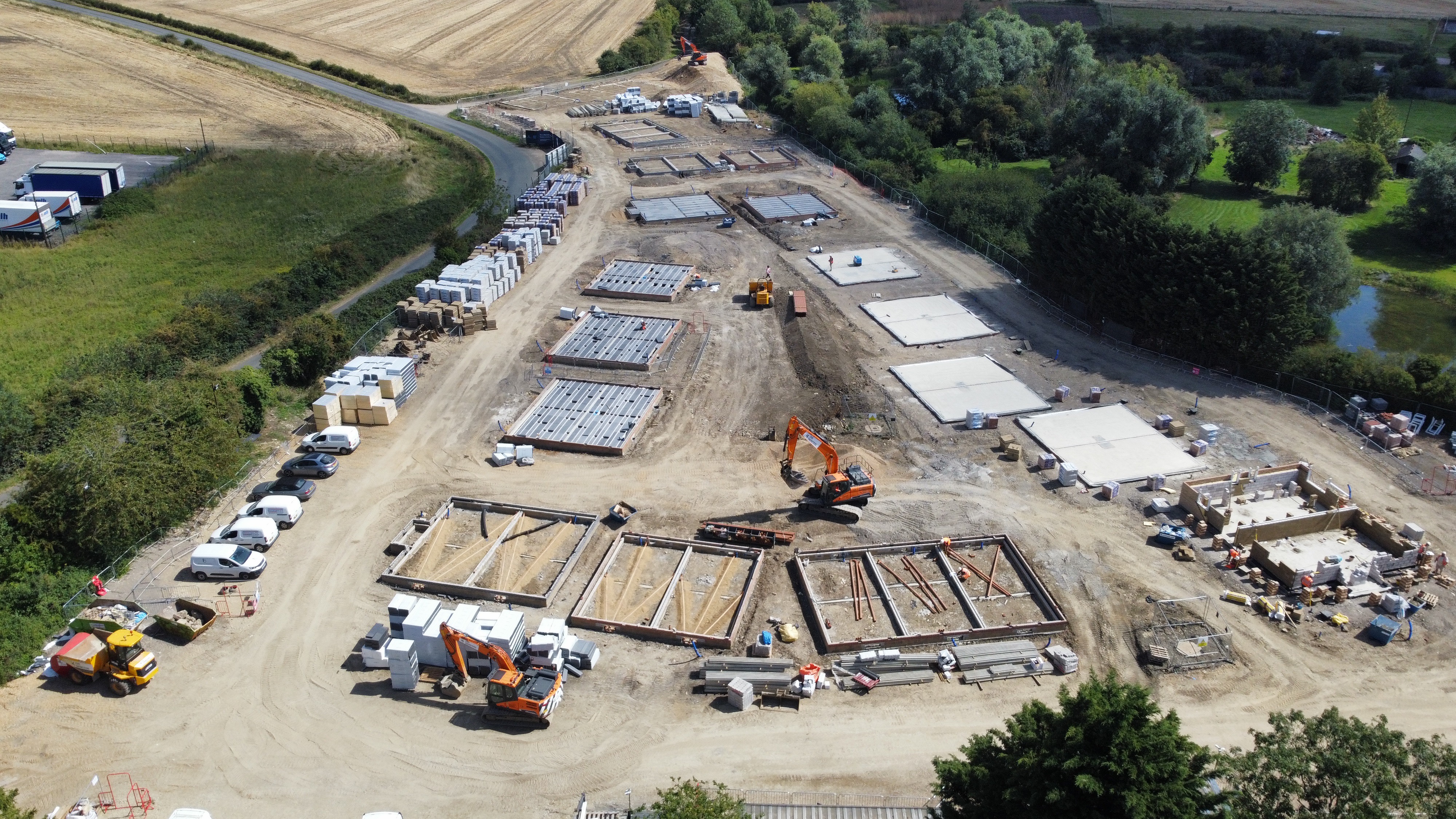 A birds-eye view of an active building site, with a number of foundations under construction 