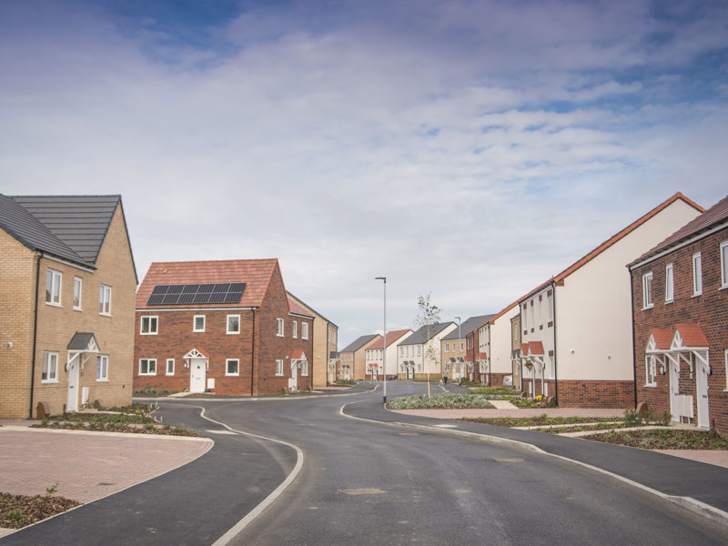 A housing development that's nearly completed, with a wide tarmac road weaving between a number of large houses